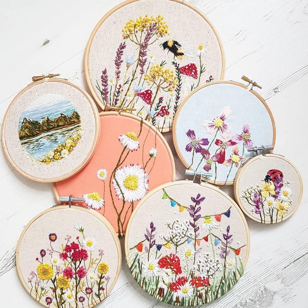 A selection of embroidery hoops with whimsical floral and landscape designs.