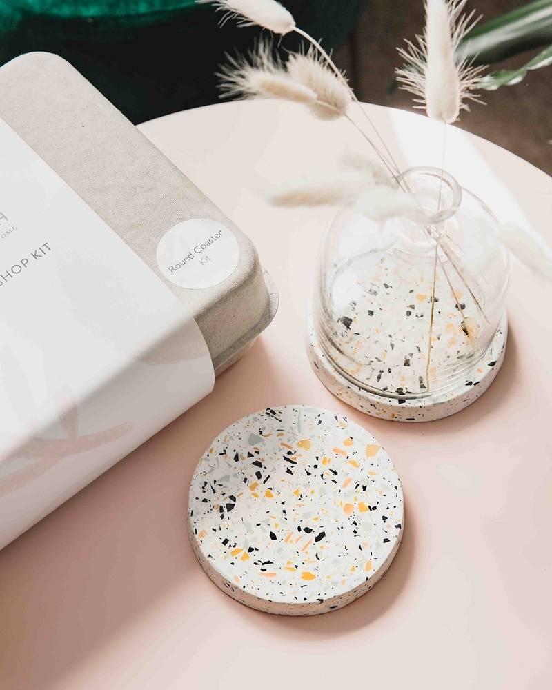 Two terrazzo coasters are styled in a modern way, with a transparent vase resting on one
