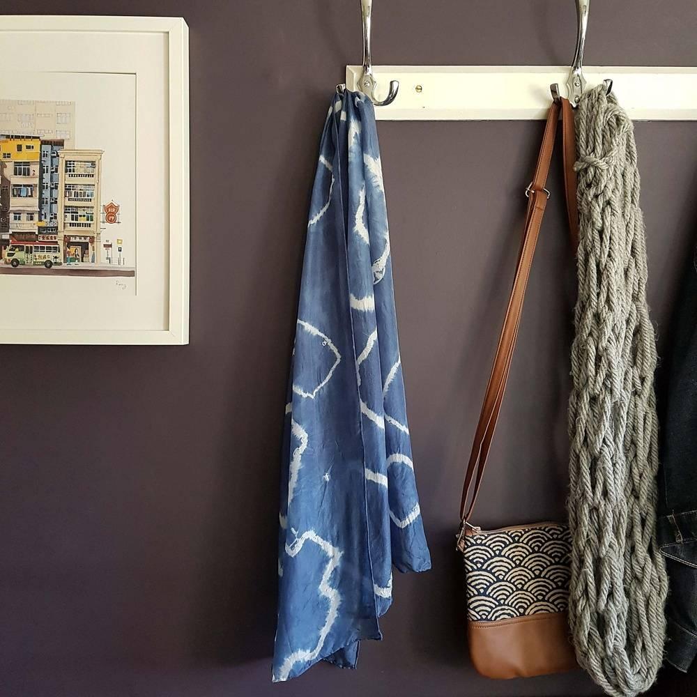 A blue and white tie dye scarf hangs from a coat peg